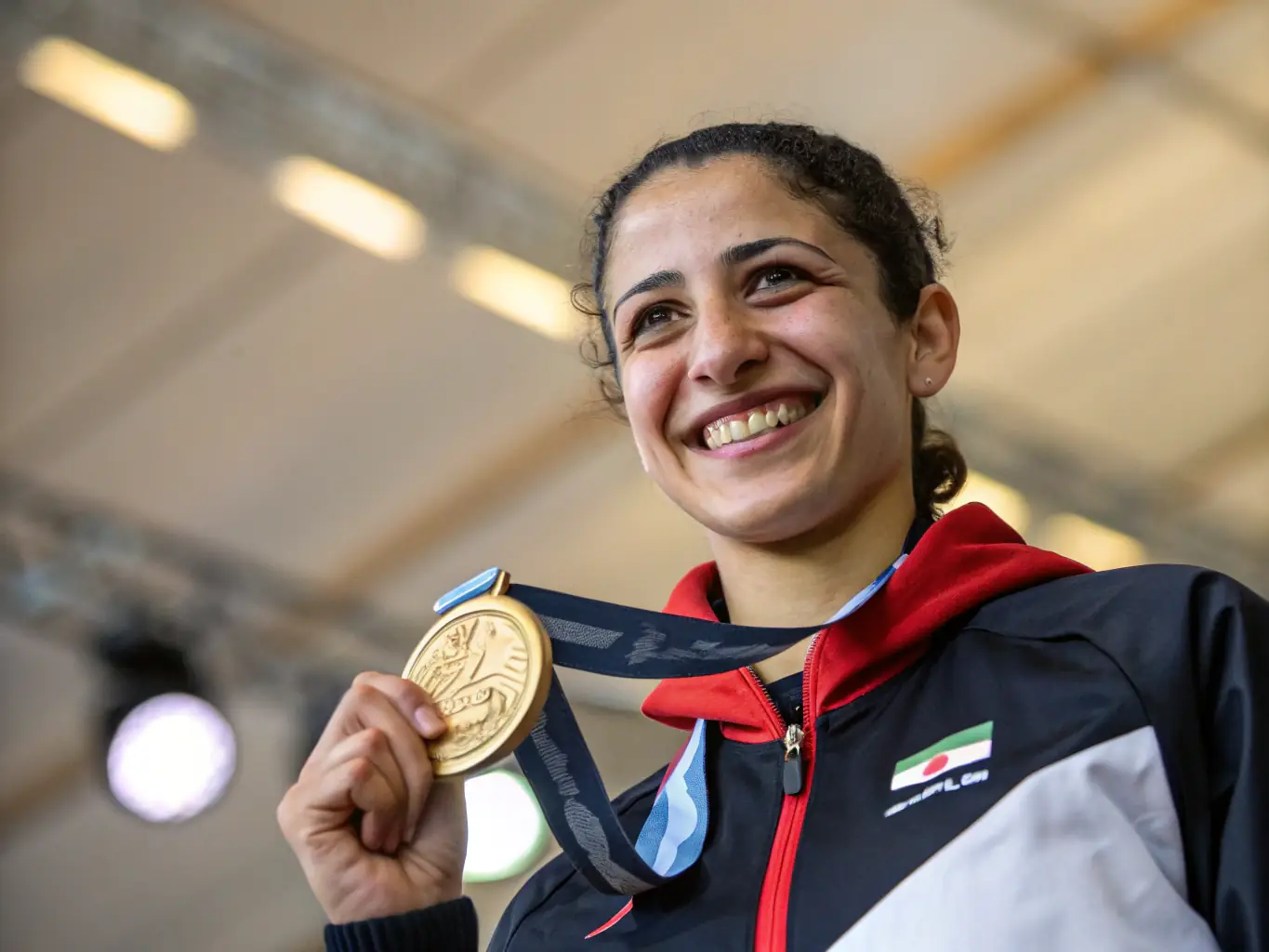 A young female athlete receiving a medal with a proud smile, highlighting the equal opportunities provided by the organization.