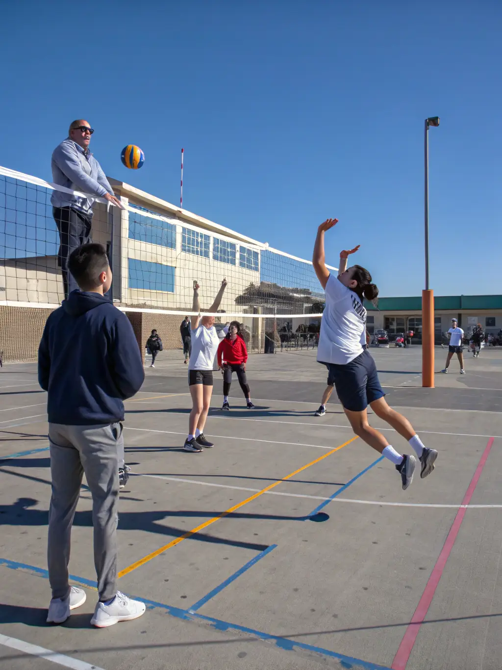 Students practicing volleyball, focusing on coordination, communication, and strategic play.